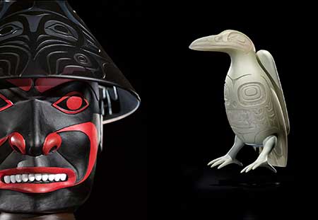 Photo of a face carved and painted and a carved raven